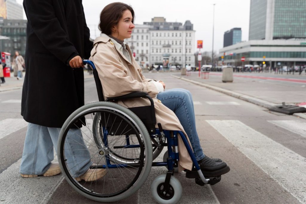 Femme en fauteuil roulant se déplaçant en toute autonomie en ville, illustrant la sécurité et l’accessibilité grâce à une assurance fauteuil roulant en France en 2025.